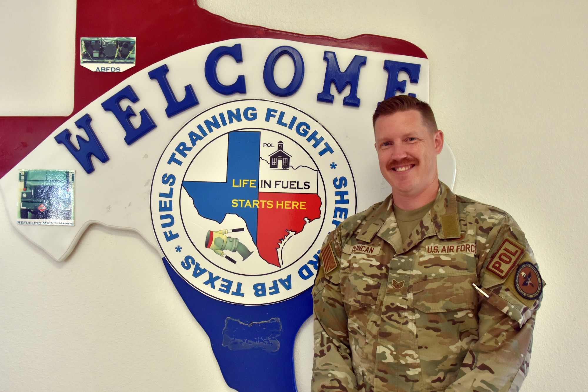 An Airman stands in front of a sign