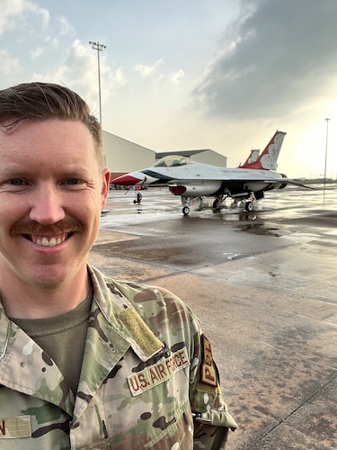An Airman stands in front of a Thunderbirds jet