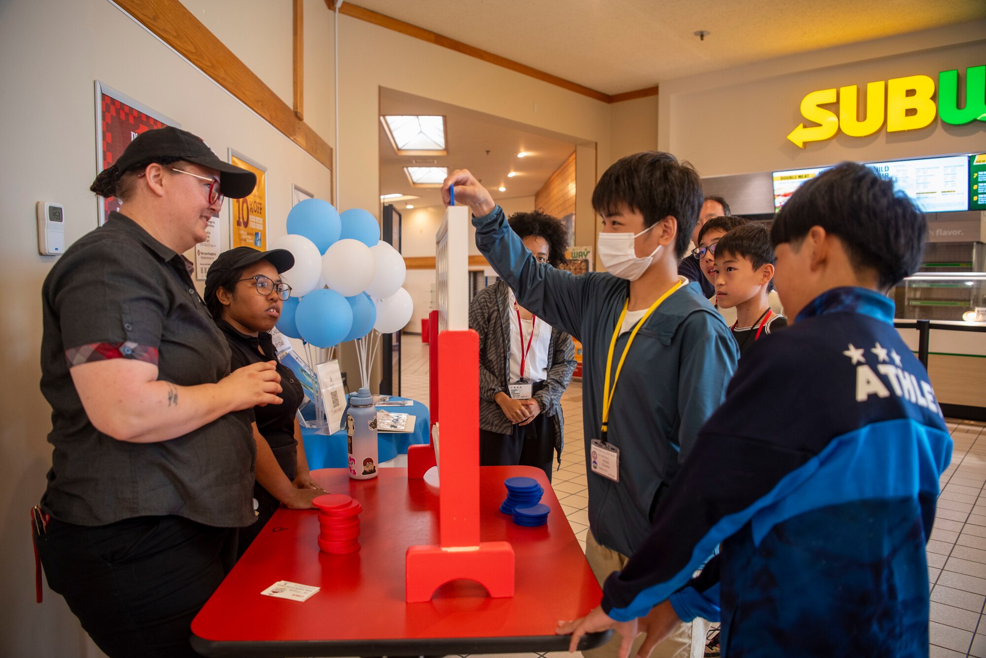 A Towada Middle School student plays Connect Four with Base Exchange food court members during a Junior English tour at Misawa Air Base, Japan, July 24, 2024.