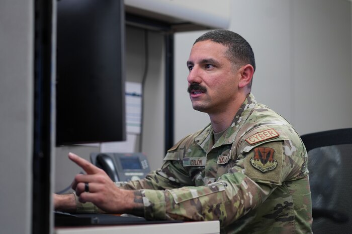 An airman points at his computer.