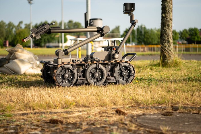 A small, six wheeled robot rolls across a lawn.