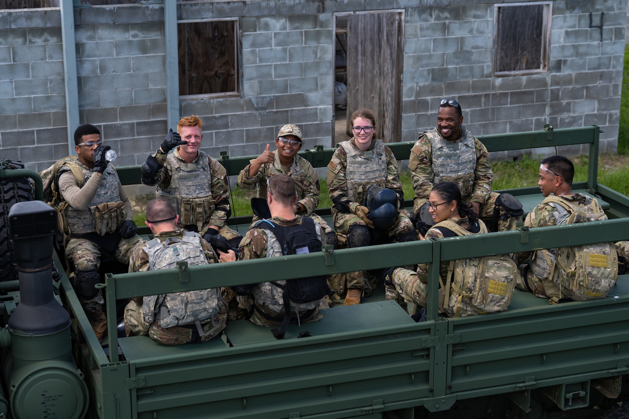 A group of Airmen sit in the back of a truck