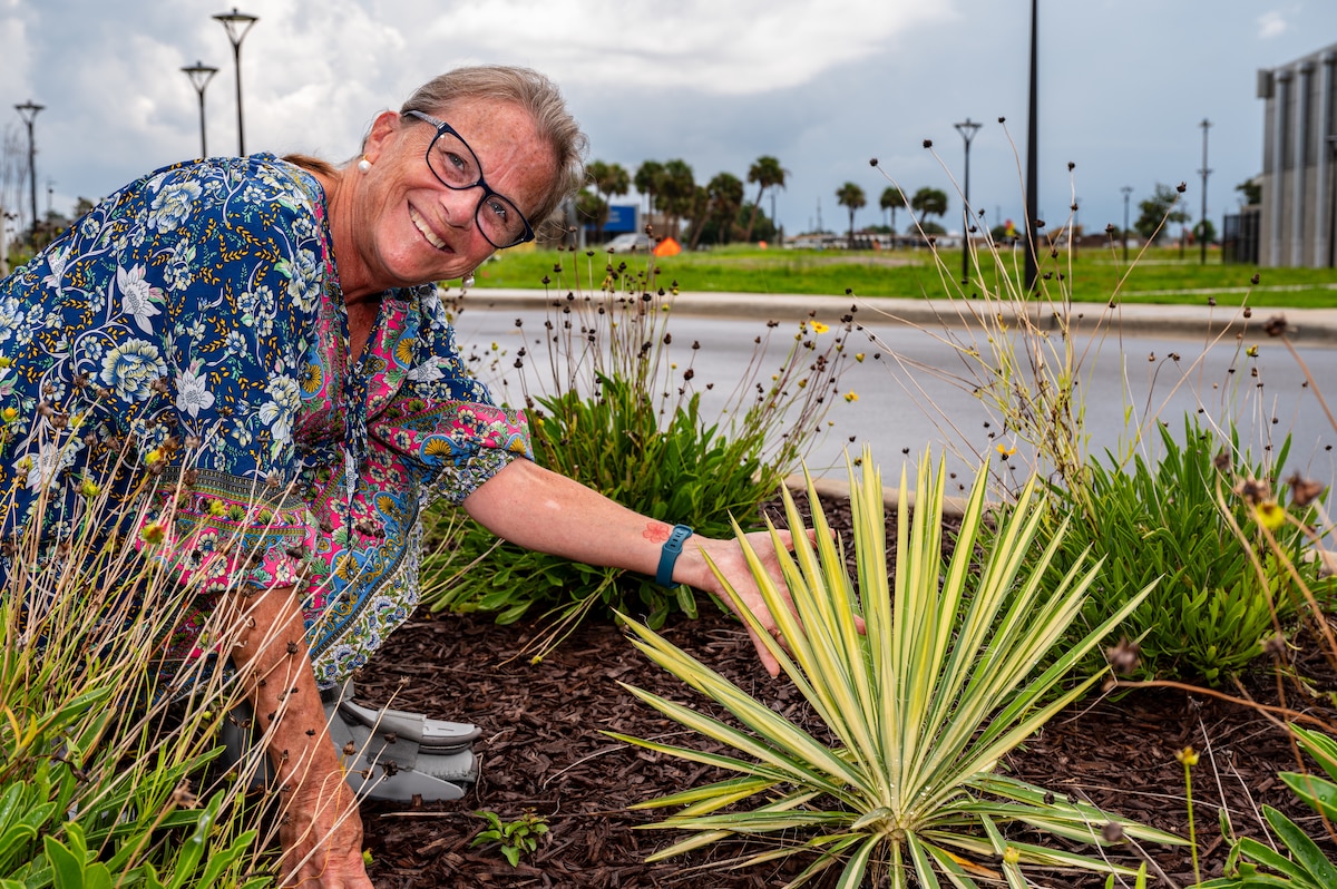 A woman showcases a variegated yucca outside of the child development center