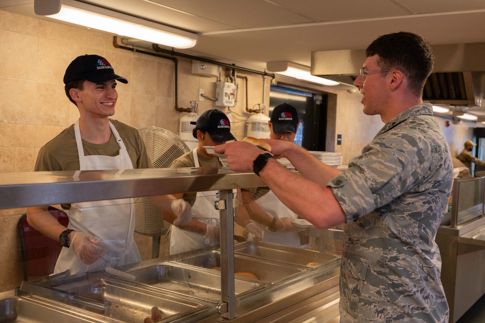 Airman serves food over counter.