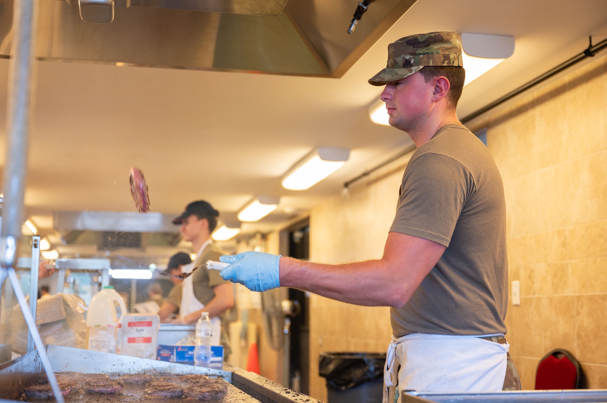 Airman flips burgers.