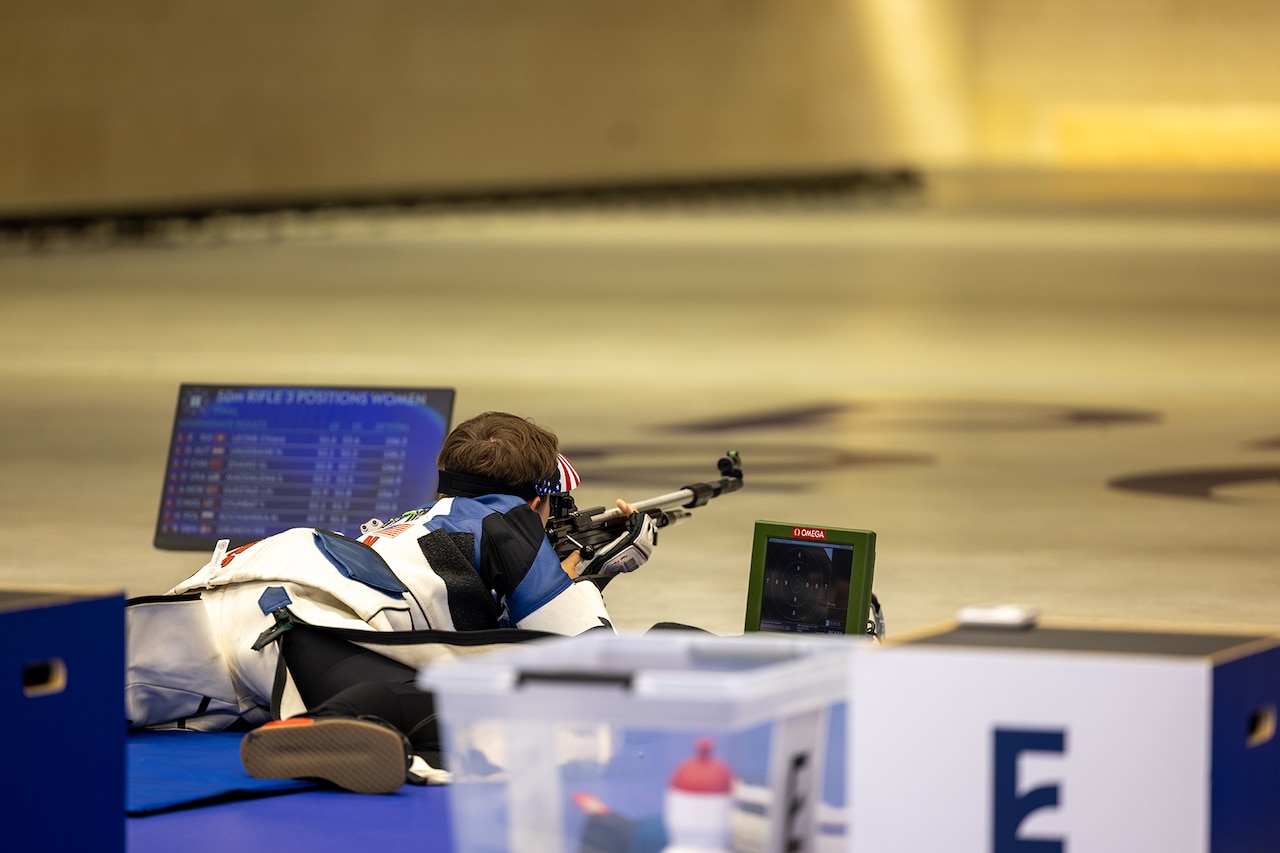 A soldier lays on the ground with a weapon during a marksmanship competition at the Summer Olympics.