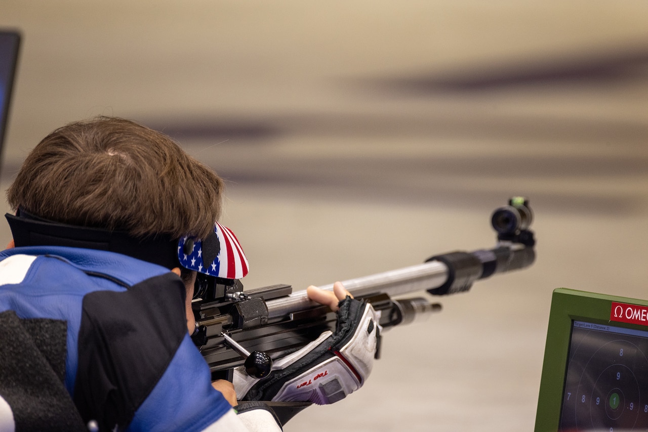 A soldier lays on the ground with a weapon during a marksmanship competition at the Summer Olympics.