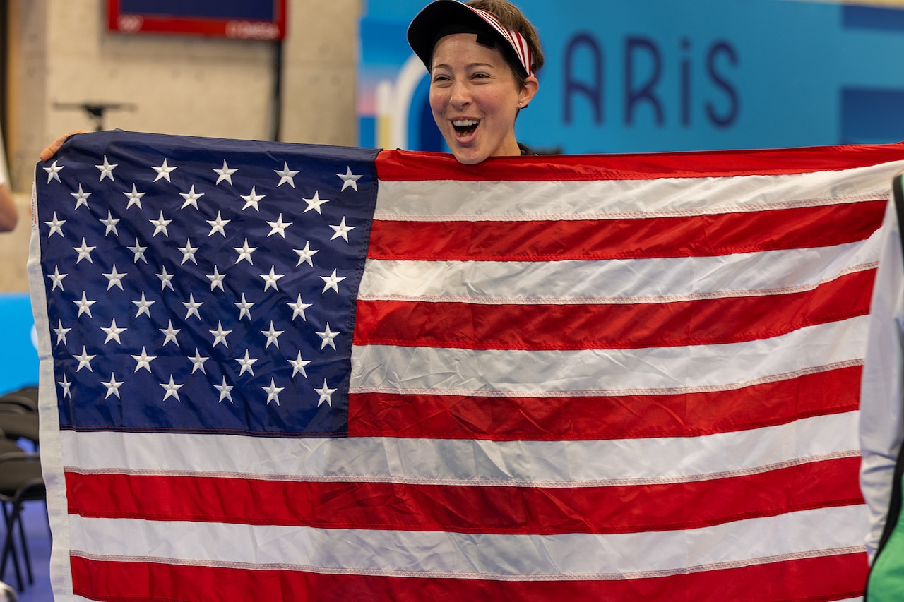A smiling soldier holds the American flag.