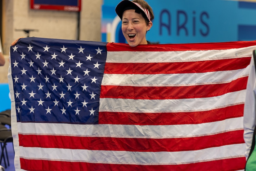 A smiling soldier holds the American flag.