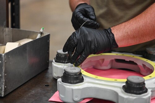 A man uses tools to make repairs in a mechanic shop.