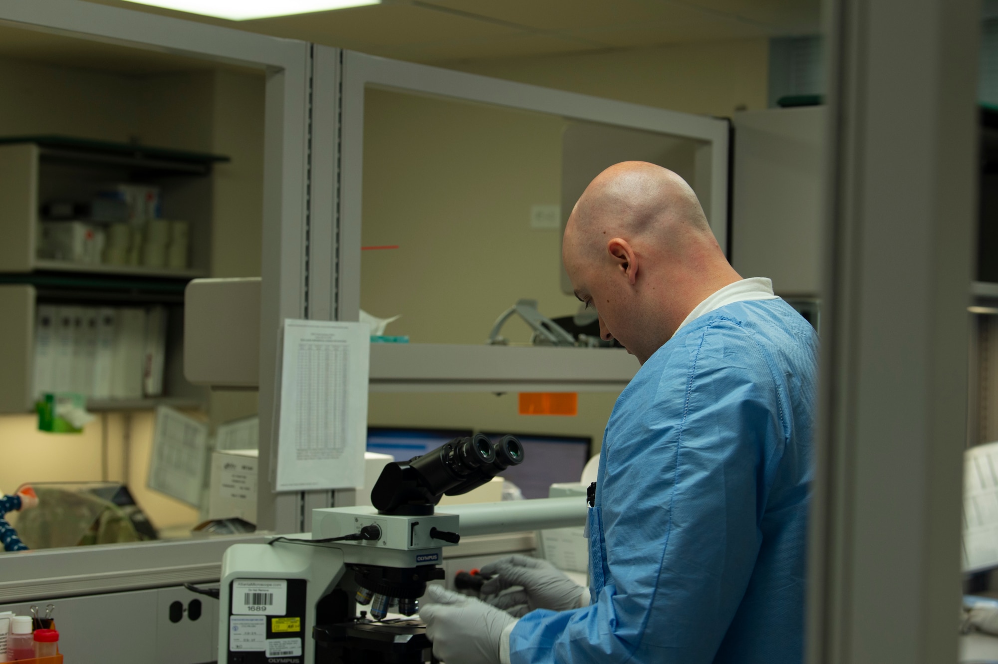 A person standing in front of a microscope in a medical office.