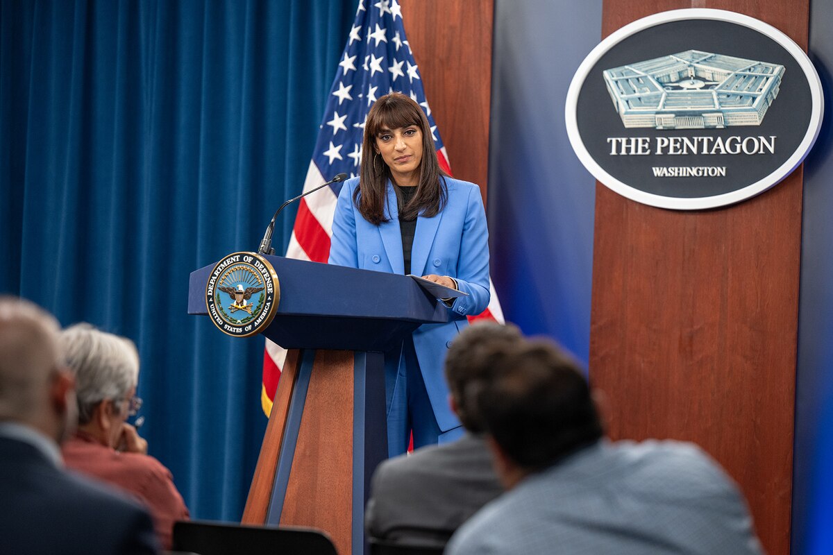 A person stands at a podium as a small audience watches.