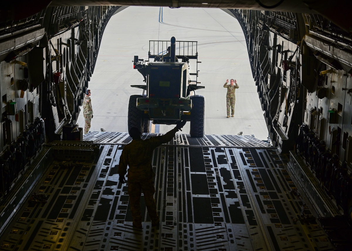 Man guides forklift onto aircraft.