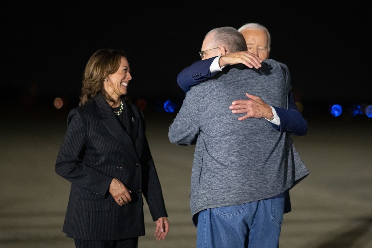 A man hugs another man next to a woman.