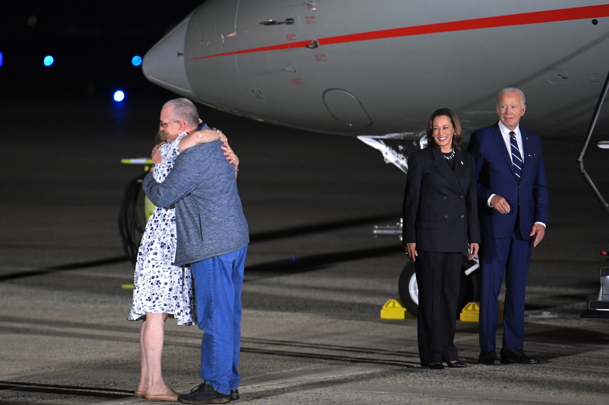 A man and woman hug while two people look on.