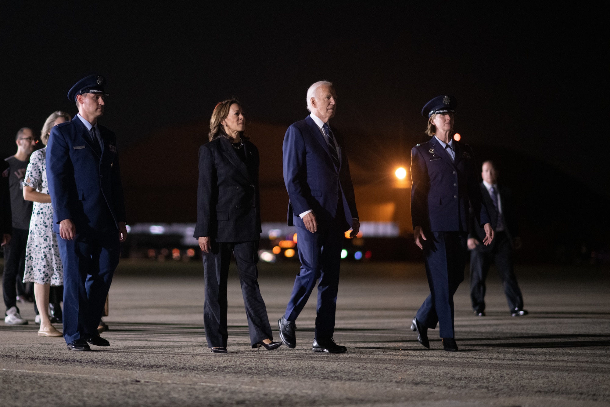 People walk in a group at night on a flight line.