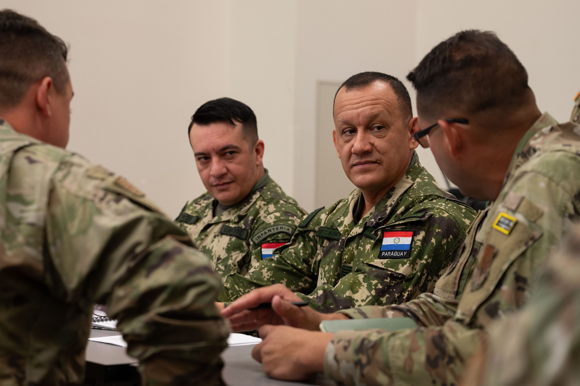 Massachusetts National Guardsmen sit at a table with members of the Paraguayan military.