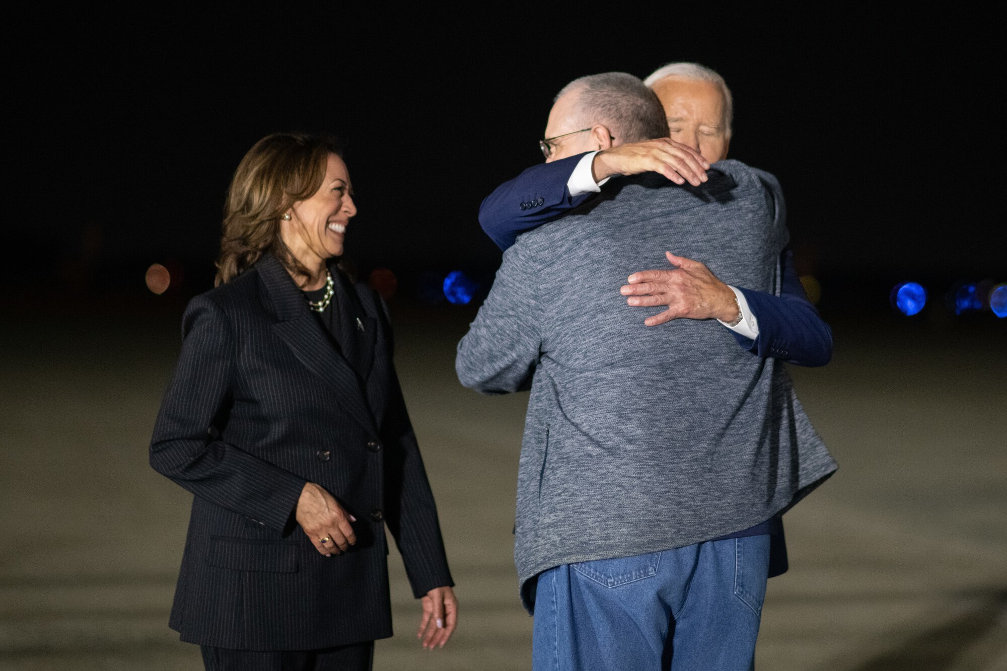 A man hugs another man next to a woman.