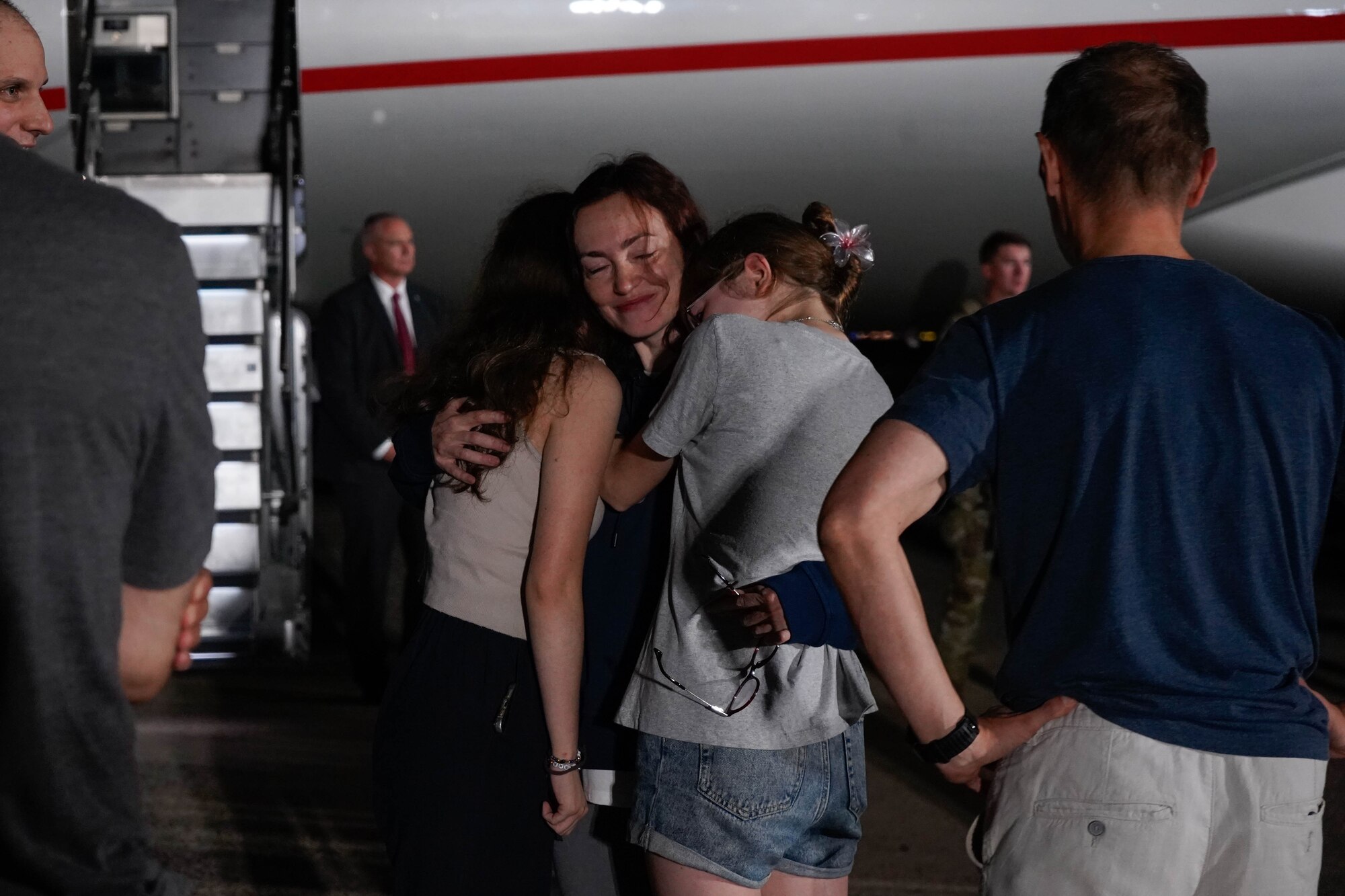 A woman hugs two girls.