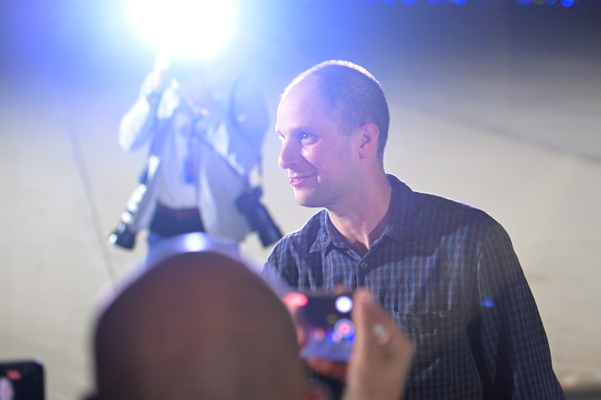 A man smiles in front of cameras.