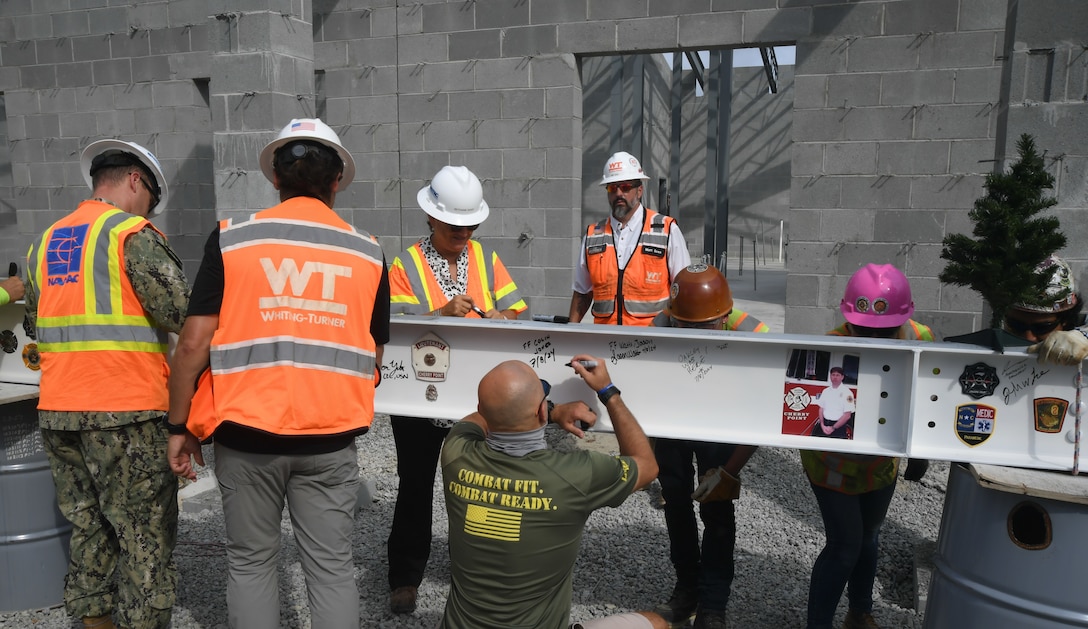 Members of Officer in Charge of Construction and contractor of record crews from Whiting and Turner Contracting Company sign the final steel beam during a topping out ceremony for Military Construction Project 142B at Marine Corps Air Station Cherry Point on July 8, 2024.