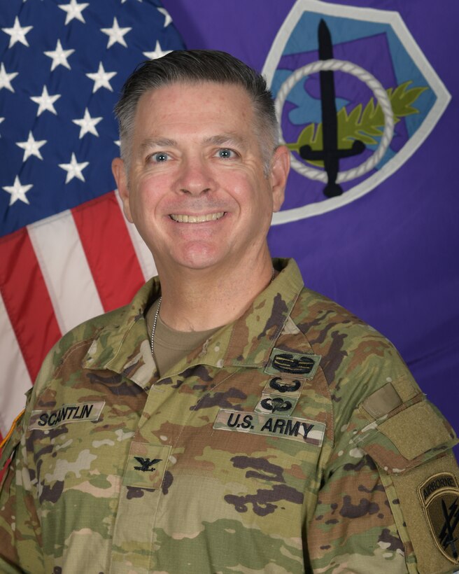 Colonel Marshall Straus Scantlin, commander, 350th Civil Affairs Command, poses in front of the US and 350th Cacom flags in his OCP uniform.