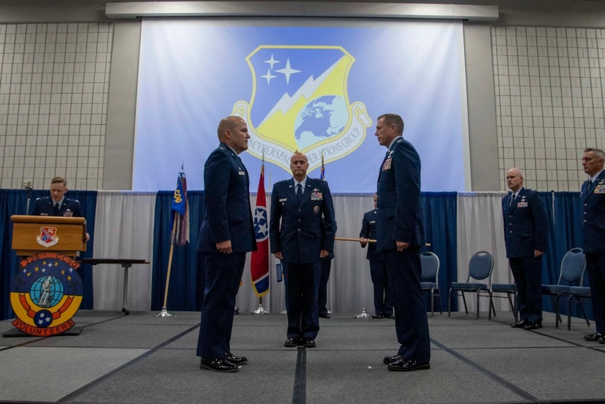 Col. Christopher Smith (left) 228th Cyberspace Operations Group commander, Col. Jason Glass (center), Tennessee Assistant Adjutant General, Air, and Col. Lee Hartley, 134th Air Refueling Wing commander, pause in front of the new 228th COG shield for the unfurling of the 228th COG guidon Aug. 4, 2024, at McGhee Tyson Air National Guard Base.