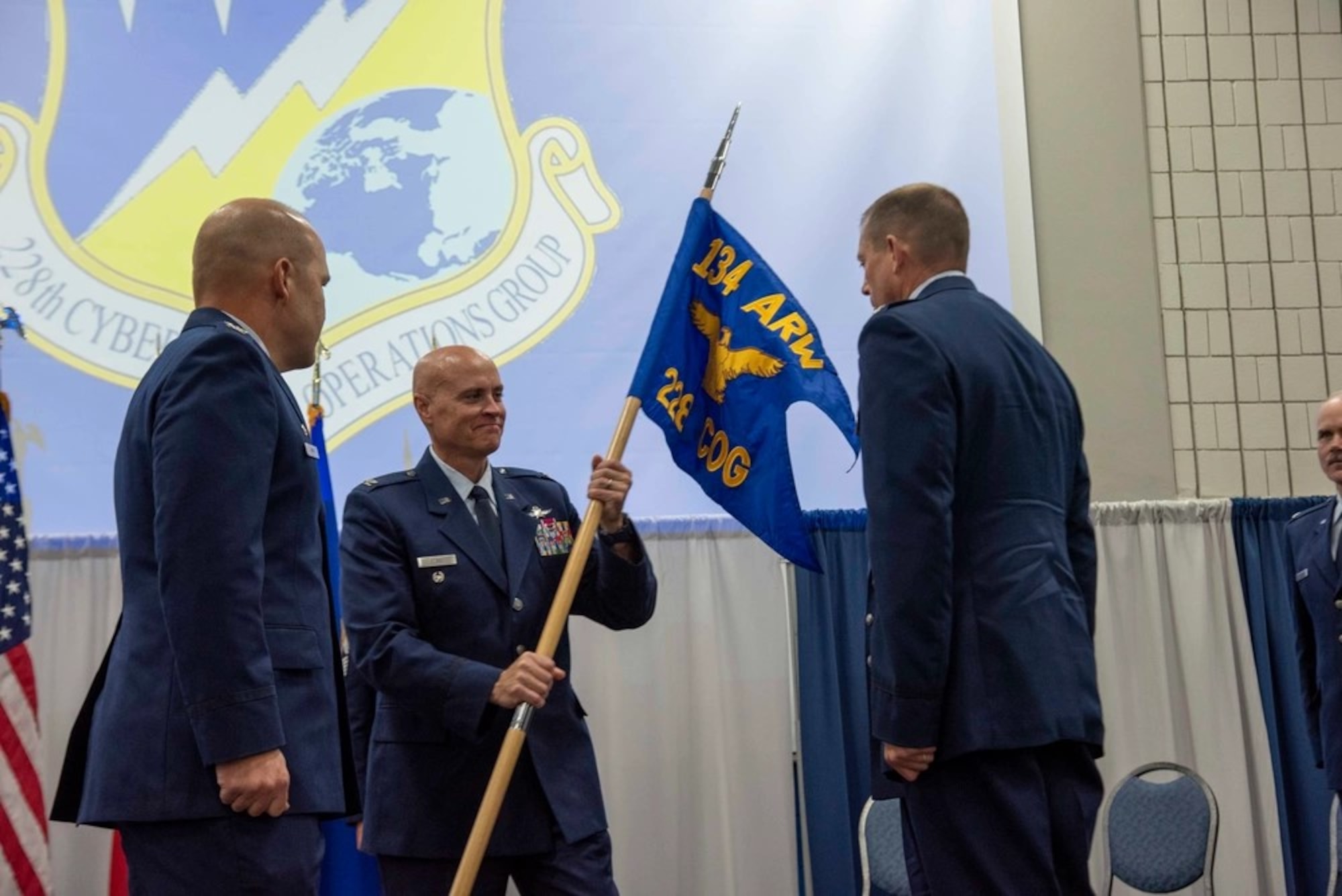 Col. Jason Glass, Tennessee Assistant General, Air, passes the new 228th Cyberspace Operations Group guidon to Col. Lee Hartley, 134th Air Refueling Wing commander Aug. 4, 2024, at McGhee Tyson Air National Guard Base.
