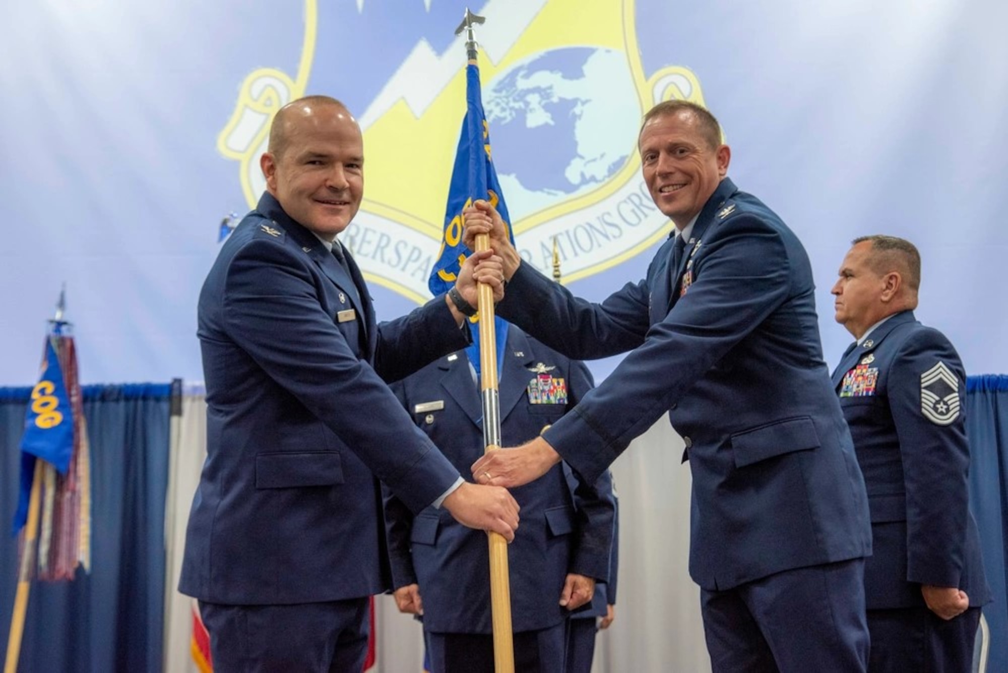Col. Lee Hartley, 134th Air Refueling Wing commander, passes the new 228th Cyberspace Operations Group guidon to Col. Christopher Smith, 228th Cyberspace Operations Group commander Aug. 4, 2024, at McGhee Tyson Air National Guard Base.