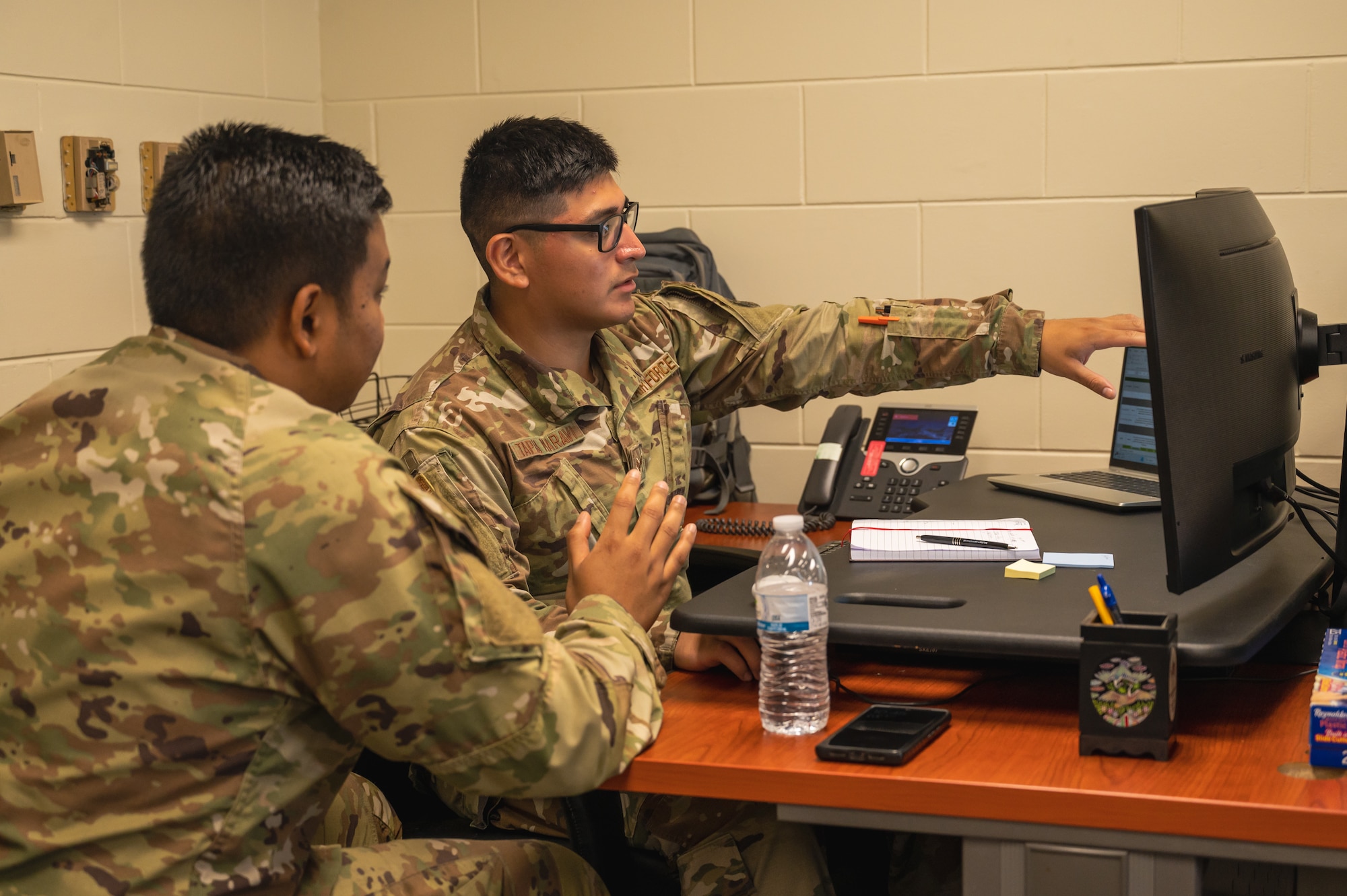 Senior Airman Gino Tapia Maravi, right, 8th Maintenance Group time compliance technical order monitor, assists Staff Sgt. Matthew Quach, 80th Fighter Generation Squadron F-16 integrated avionics technician craftsman, with scheduling maintenance.