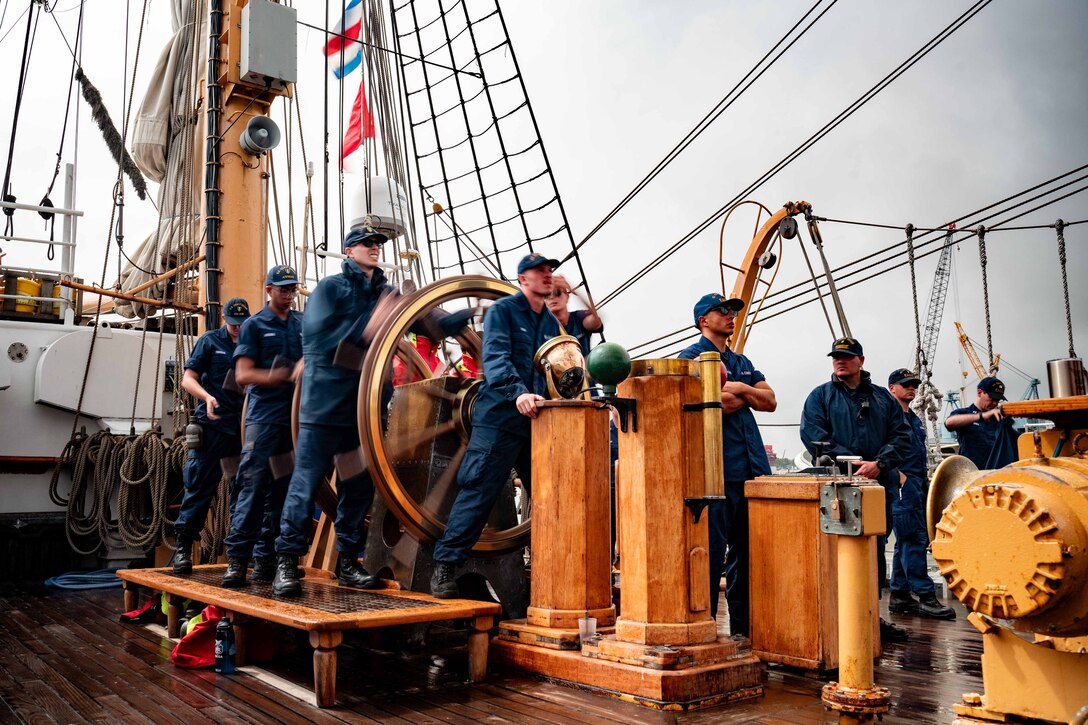 Coast Guard cadets stand on the deck of a ship performing various tasks.