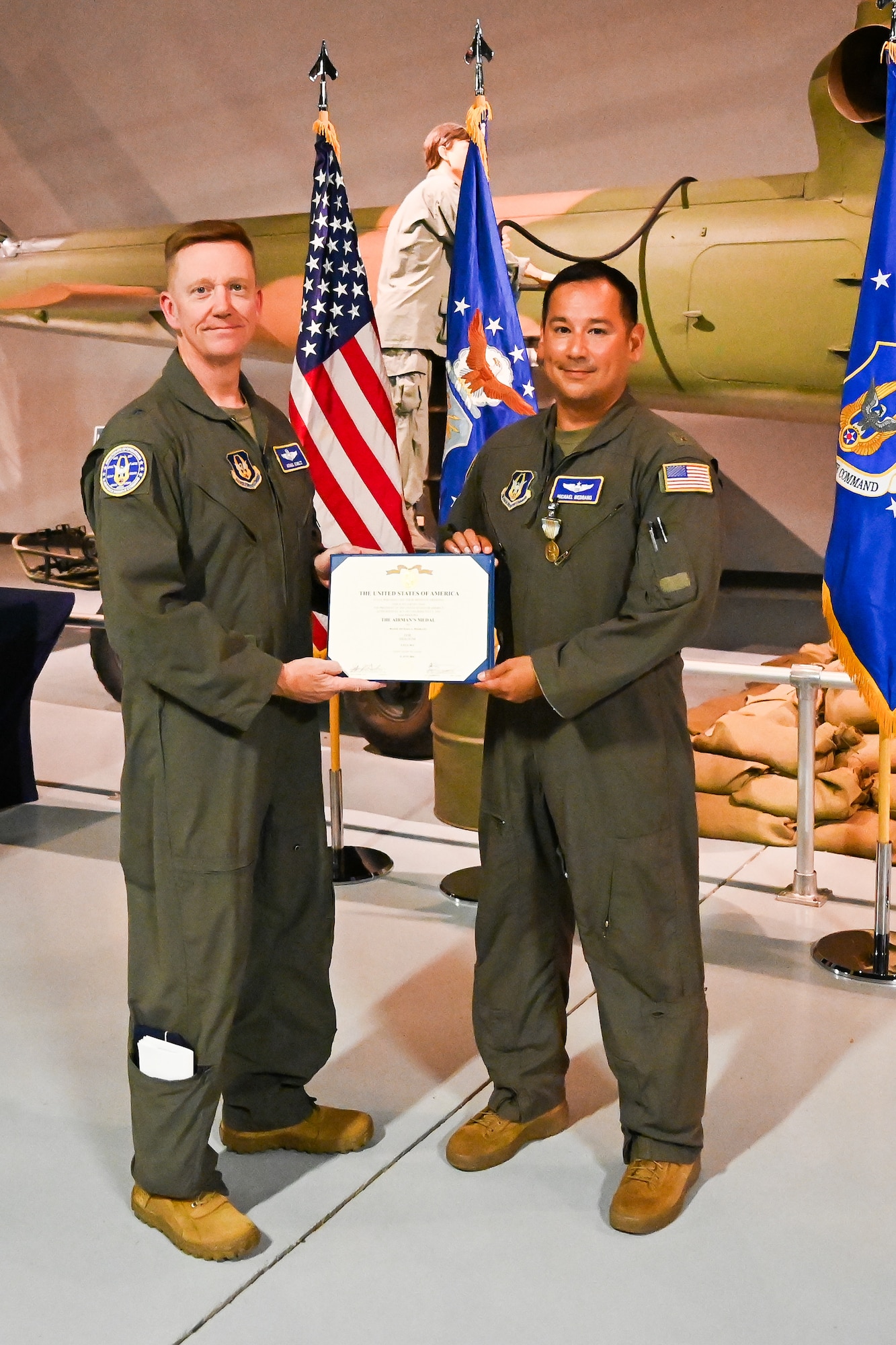 Photo of two Airmen holding an award between them.