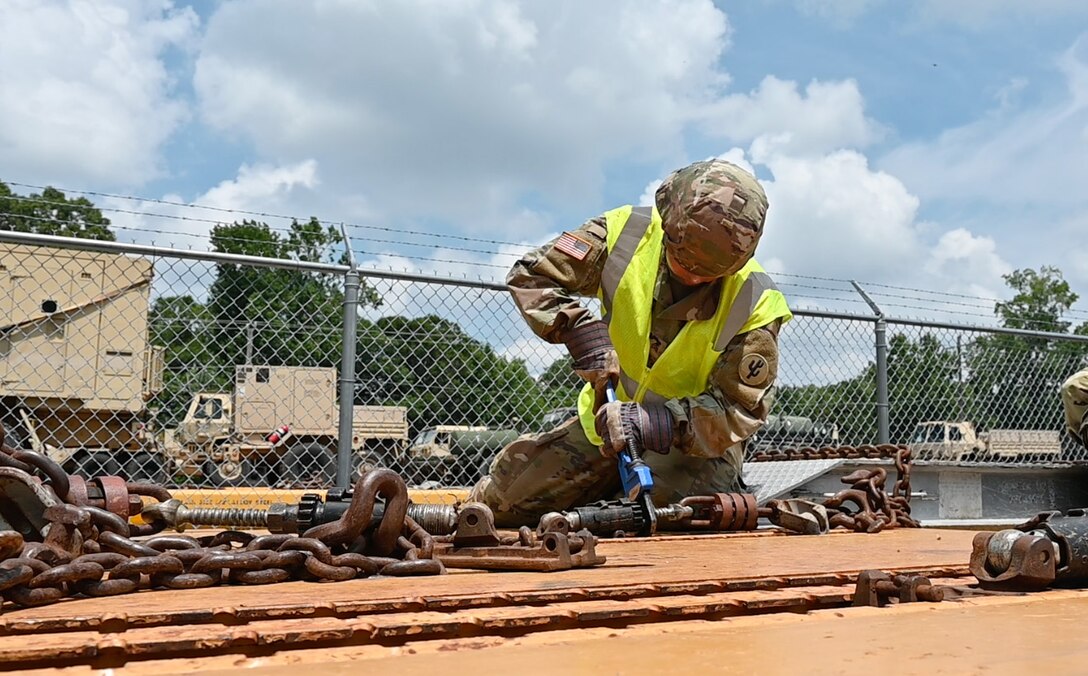 A Soldier tightens a chain with a wrench