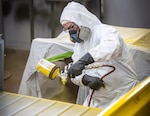 Chris Gaden, painter/blaster, Shop 71, Painters, Blasters and Tile Setters, sprays the bed of a Tiger mini-truck with a base coat of yellow paint July 25, 2024, during a project for Code 710, Special Projects at Puget Sound Naval Shipyard & Intermediate Maintenance Facility in Bremerton, Washington. (U.S. Navy photo by Jeb Fach)