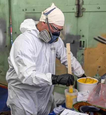 Chris Gaden, painter/blaster, Shop 71, Painters, Blasters and Tile Setters, mixes yellow paint with a reducing agent July 25, 2024, while preparing a base coat for a unique painting project for Code 710, Special Projects, inside Building 873 at Puget Sound Naval Shipyard & Intermediate Maintenance Facility in Bremerton, Washington. (U.S. Navy photo by Jeb Fach)