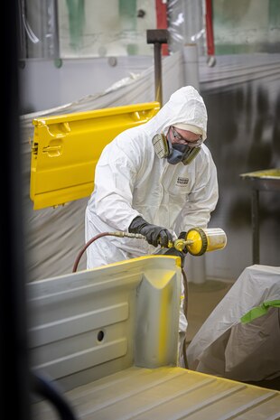 Chris Gaden, painter/blaster, Shop 71, Painters, Blasters and Tile Setters, sprays the bed of a Tiger mini-truck with a base coat of yellow paint July 25, 2024, during a special painting project for Code 710, Special Projects, at Puget Sound Naval Shipyard & Intermediate Maintenance Facility in Bremerton, Washington. (U.S. Navy photo by Jeb Fach)