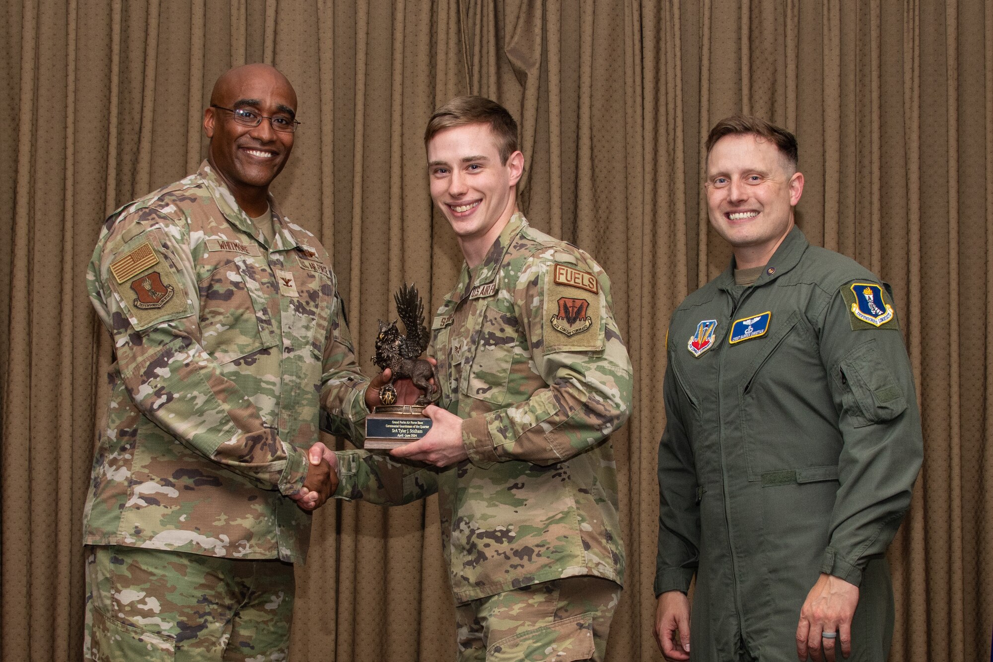 A military member stands on stage to accept an award.