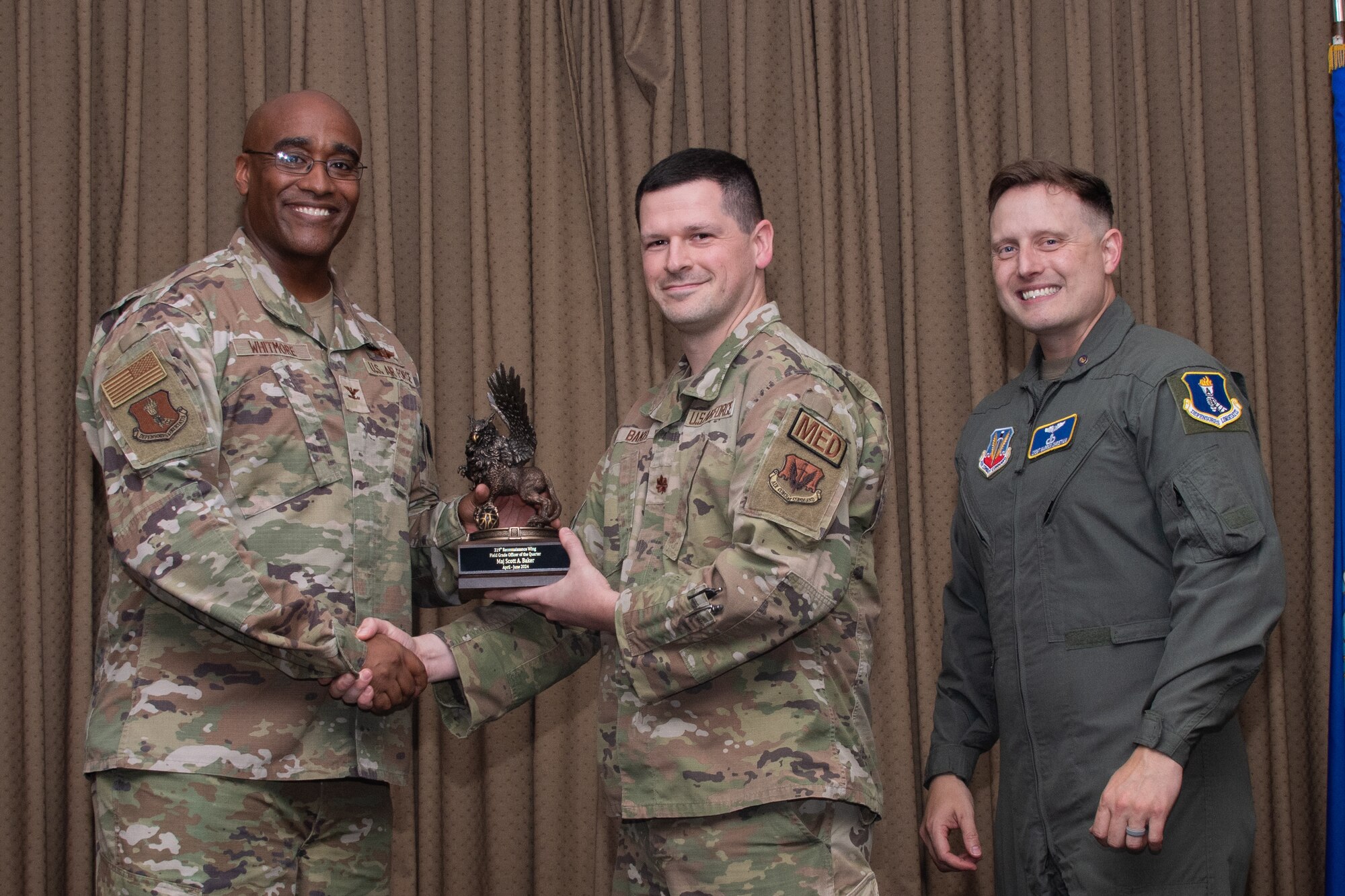 A group of military members stand on stage to accept an award.