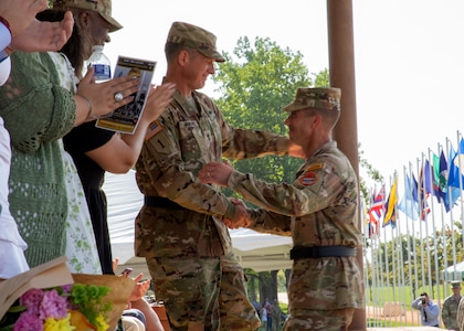 Outgoing Commanding General of the U.S. Army Cyber Center of Excellence congratulates the incoming Commanding General Maj. Gen. Ryan Janovic after a Change of Command ceremony Aug. 2, 2024, at Barton Field on Fort Eisenhower, Ga.