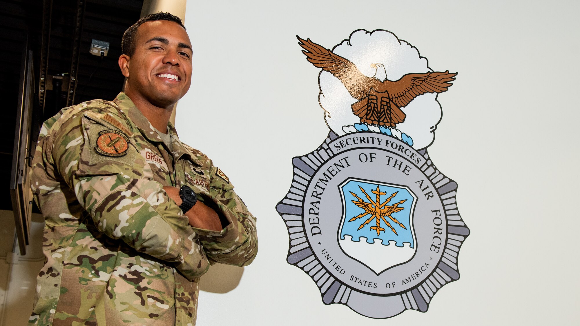 A portrait of an Airman in front of the security forces badge on a wall