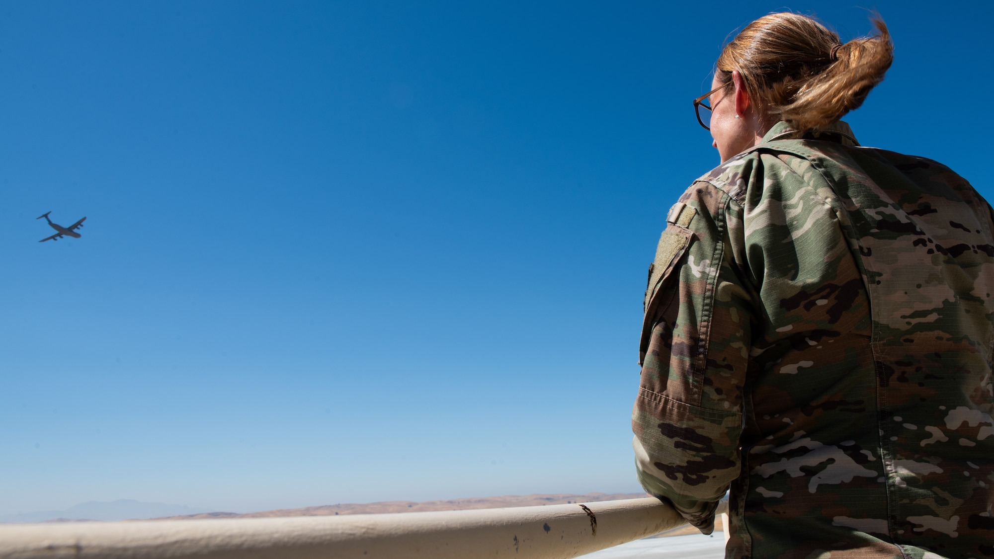 Command chief observes a C-5 fly by from the air traffic control tower catwalk.