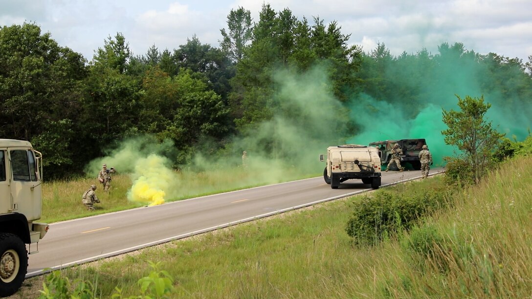 Soldiers from the 402nd Quartermaster Battalion react to an ambush during WAREX, July 24, 2024, at Fort McCoy, Wis. Army Maj. Herb Karg and OC/T with the 87th Training command observes the event. (Photo by Sgt. 1st Class Justin Hardin)