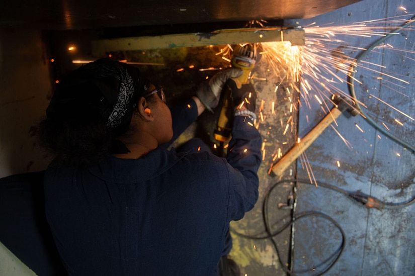 Sparks fly as a sailor grinds steel.