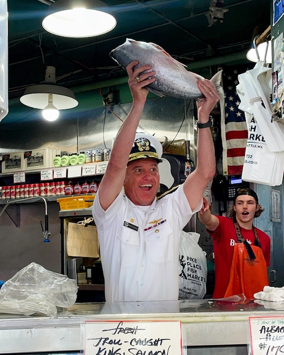 U.S. Navy Rear Adm. Mark Sucato, commander of Navy Region Northwest, celebrates after catching a fish at Pike Place Market in Seattle during Seattle Seafair Fleet Week July 31, 2024. Seattle Fleet Week is a time-honored celebration of the sea services and provides an opportunity for the citizens of Washington to meet Sailors, Marines and Coast Guardsmen, as well as witness firsthand the latest capabilities of today’s maritime services.  (U.S. Navy photo by Chief Mass Communication Specialist Gretchen Albrecht)