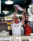 U.S. Navy Rear Adm. Mark Sucato, commander of Navy Region Northwest, celebrates after catching a fish at Pike Place Market in Seattle during Seattle Seafair Fleet Week July 31, 2024. Seattle Fleet Week is a time-honored celebration of the sea services and provides an opportunity for the citizens of Washington to meet Sailors, Marines and Coast Guardsmen, as well as witness firsthand the latest capabilities of today’s maritime services.  (U.S. Navy photo by Chief Mass Communication Specialist Gretchen Albrecht)