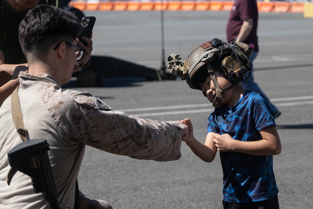 U.S. Marine Corps Cpl. Ethan Kirtley, left, a recapture tactics team member with Marine Corps Security Force Battalion, Bangor, fist bumps a child at a static display of weapons and equipment during Seattle Seafair Fleet Week in Seattle, Aug. 3, 2024. The U.S. Navy, Coast Guard, and Marines have been involved in Seafair in some way since the festival began 75 years ago. The annual event provides service members an opportunity to interact with the American people and promotes the Navy-Marine Corps team as the nation’s expeditionary force in readiness. Kirtley is a native of Missouri. (U.S. Marine Corps photo by Sgt. Cameron Hermanet)