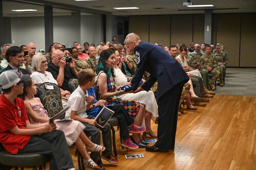 A man gives a woman flowers at a ceremony.