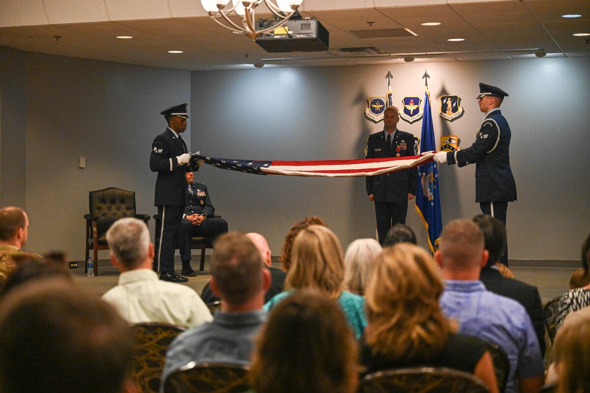 Men fold a flag at a ceremony.