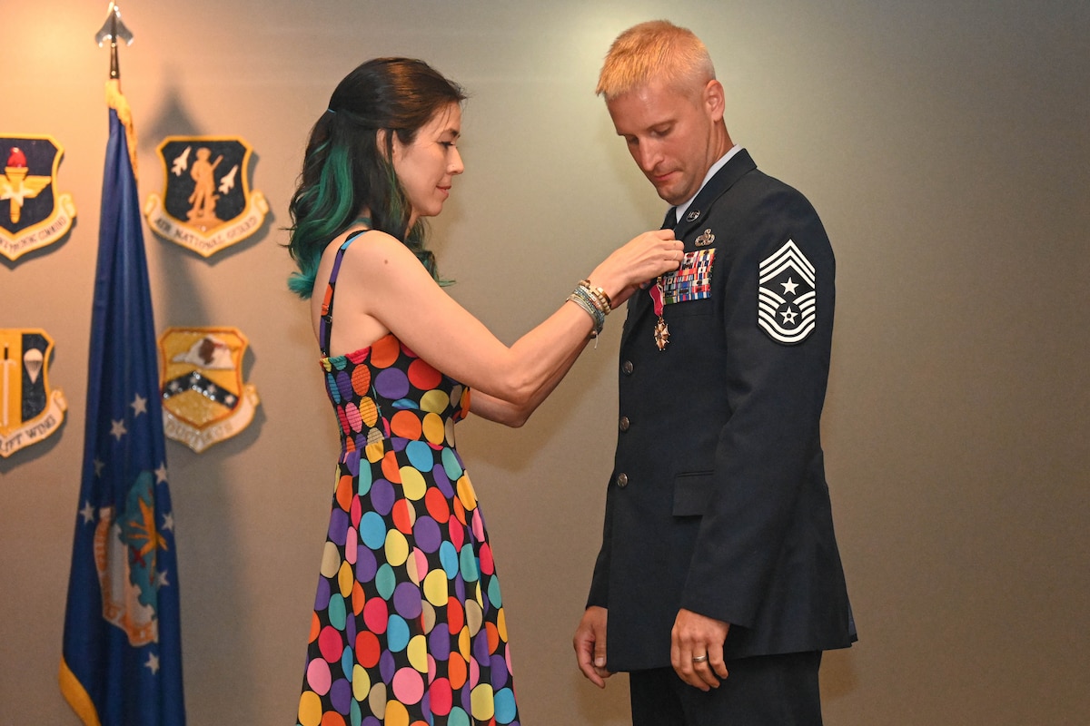 A young woman pins a man at a ceremony.