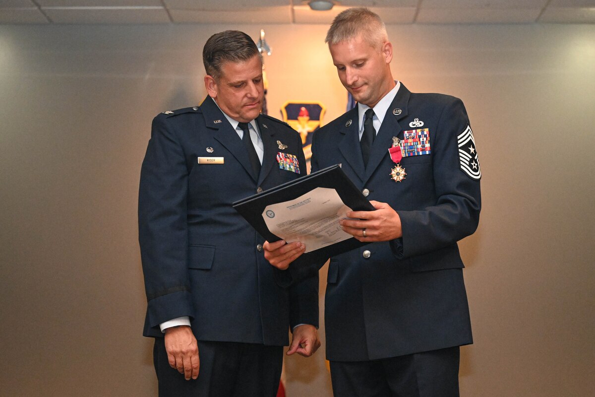 A man presents another man with a certificate.
